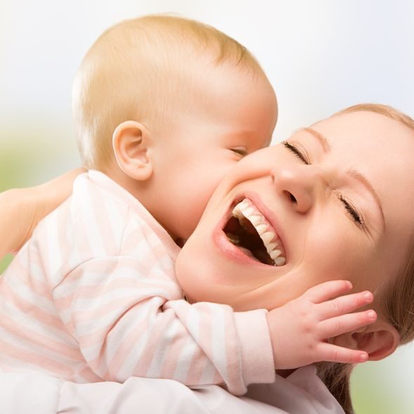 18283380 - happy cheerful family. mother and baby kissing, laughing and hugging